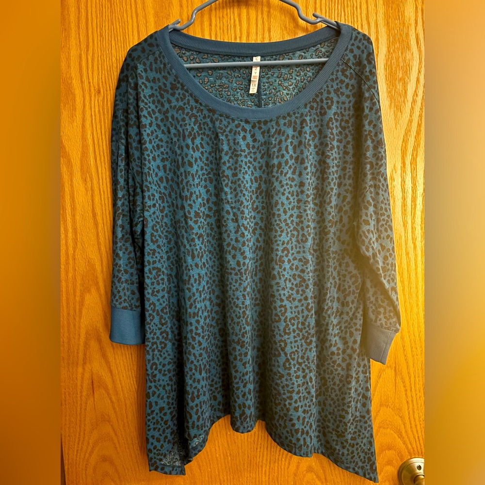 Size 1X LuLaRoe top with black animal print on a blue background. Shark bite hem